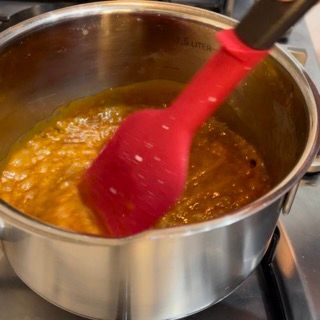 Una pentola di salsa con dentro una spatola rossa