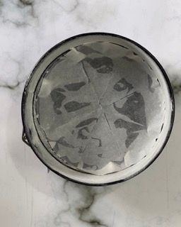 Una tortiera è appoggiata su un bancone di marmo.