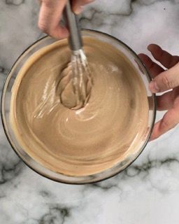 Una persona sta mescolando qualcosa in una ciotola con una frusta.