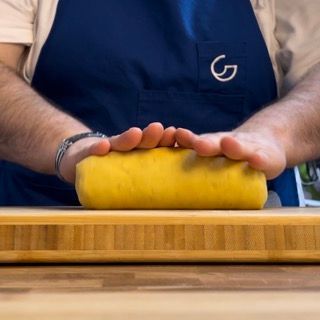 Un uomo con un grembiule tiene in mano un oggetto giallo su un tagliere
