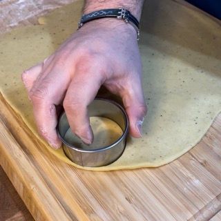 Una persona sta usando un tagliabiscotti per tagliare un pezzo di pasta