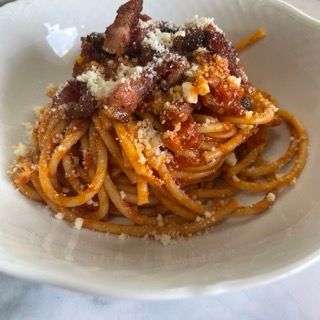 Un primo piano di una ciotola di spaghetti con pancetta e formaggio