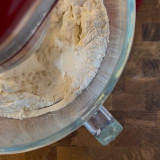 Una ciotola di vetro piena di farina su un tavolo di legno