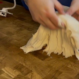 Una persona tiene in mano un pezzo di pasta su un tagliere