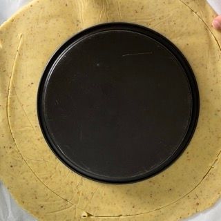 Una teglia per pizza è appoggiata su un pezzo di pasta.