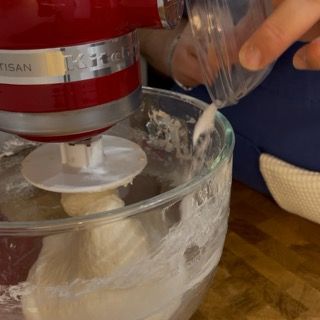 Una persona sta versando qualcosa in un mixer KitchenAid