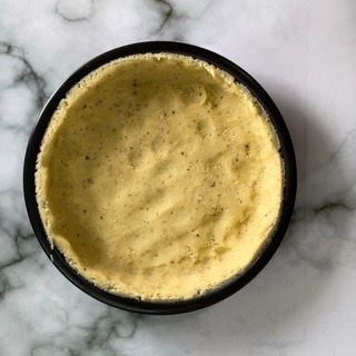 Una ciotola di salsa gialla è su una superficie di marmo