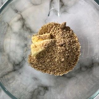 Una ciotola di vetro piena di noci e burro con un cucchiaio dentro