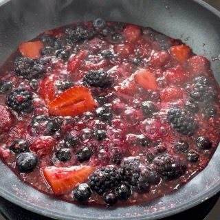 Una padella piena di bacche tra cui more e fragole