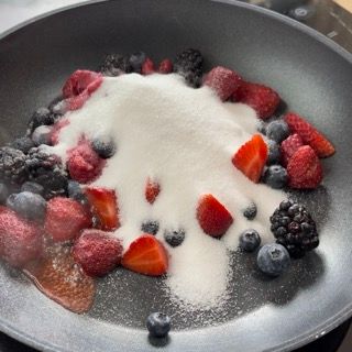 Una padella piena di fragole mirtilli more e zucchero