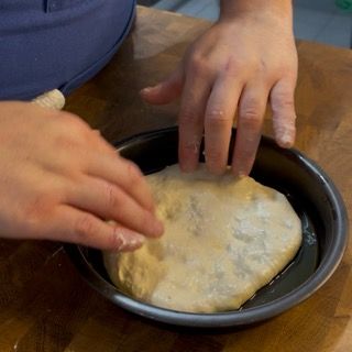 Una persona sta mettendo un pezzo di pasta in una padella