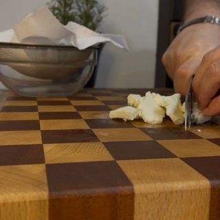 Una persona sta tagliando il burro su un tagliere a scacchi