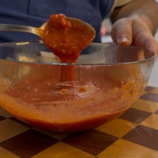 Una persona sta versando la salsa in una ciotola con un cucchiaio