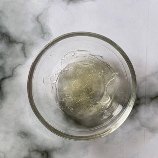 Una ciotola di vetro piena di liquido è appoggiata su un tavolo.