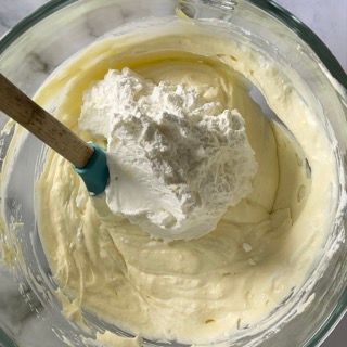 Una ciotola di panna montata con un cucchiaio di legno dentro