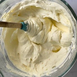 Una ciotola di panna montata con un cucchiaio di legno dentro