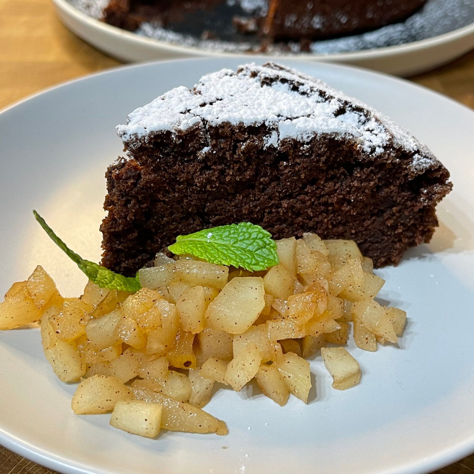 Un piatto bianco sormontato da una fetta di torta al cioccolato e mele