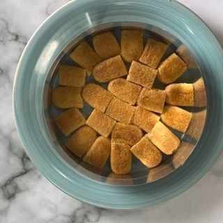 Una ciotola blu piena di quadratini di cibo su un tavolo