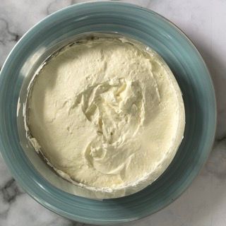 Una ciotola blu piena di panna montata su un tavolo