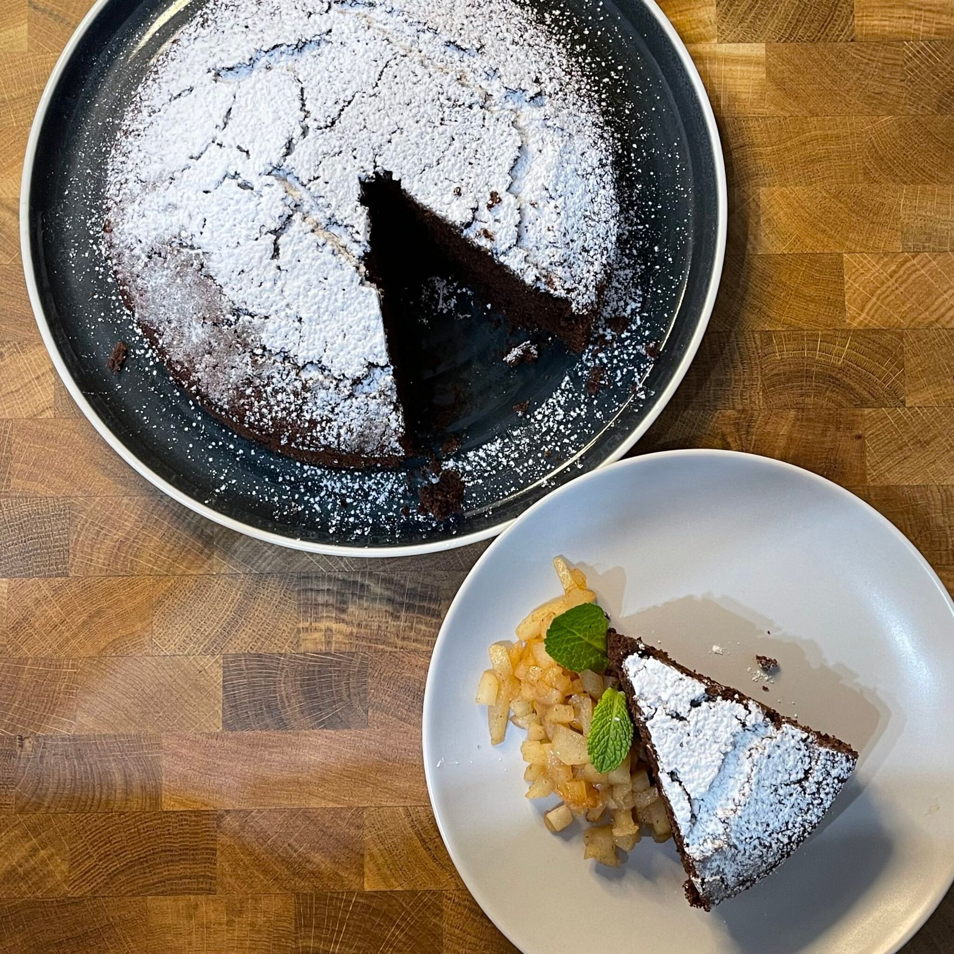 Una torta al cioccolato con zucchero a velo e una fetta su un piatto