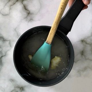 Una persona tiene un cucchiaio in una pentola di liquido