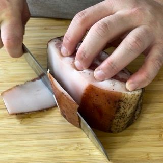 Una persona sta tagliando un pezzo di carne su un tagliere