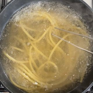 Gli spaghetti vengono cotti in una pentola d'acqua sul fornello.