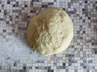 Una palla di pasta è appoggiata su un bancone piastrellato.