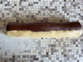 Un pezzo di cioccolato e pasta bianca è appoggiato su un bancone piastrellato.