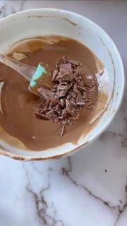 Una ciotola di salsa al cioccolato con un cucchiaio dentro su un tavolo.