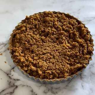 Una torta con la copertura di briciole è appoggiata su una superficie di marmo