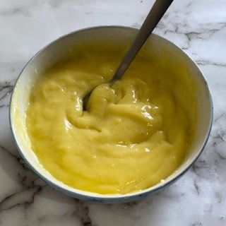 Una ciotola di salsa gialla con un cucchiaio dentro