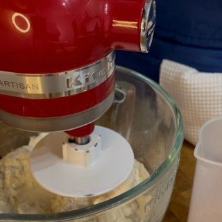 Un mixer kitchenaid rosso mescola gli ingredienti in una ciotola di vetro