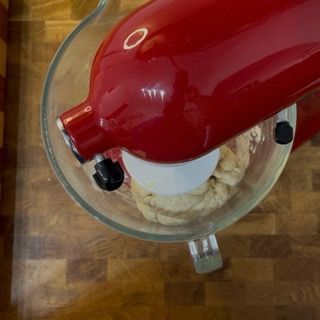 Un mixer kitchenaid rosso è appoggiato su un bancone di legno