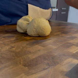 Una persona sta impastando la pasta su un tagliere di legno