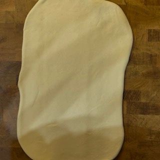 Un pezzo di pasta è appoggiato su un tavolo di legno.