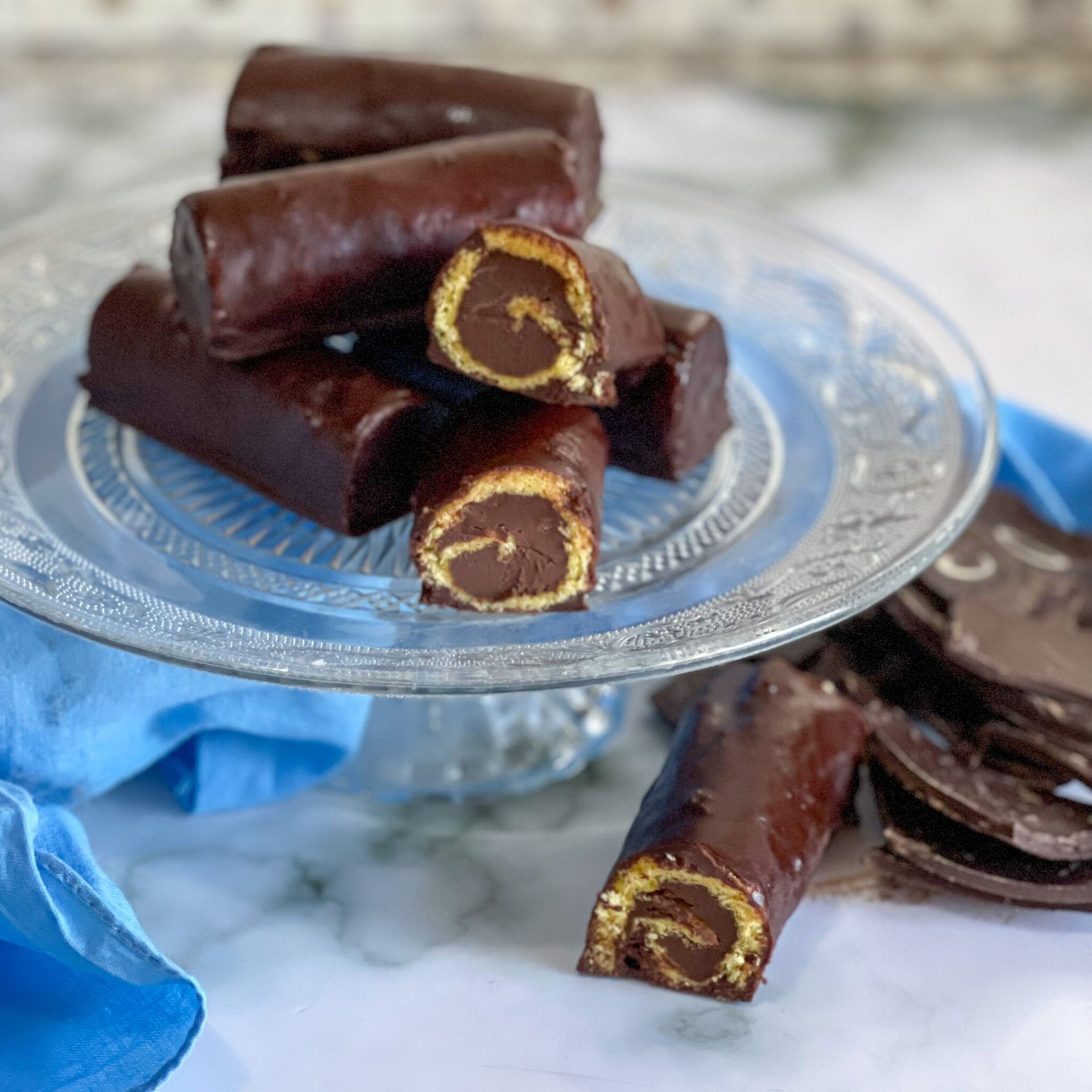 Un piatto di vetro ricoperto di rotolini di cioccolato e biscotti.