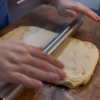Una persona sta stendendo un pezzo di pasta con un mattarello