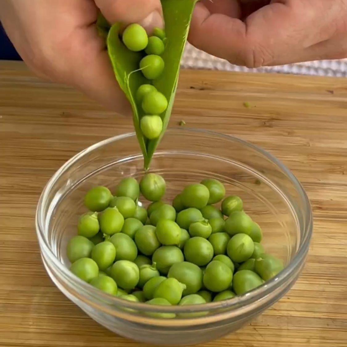 Una persona sta tirando fuori i piselli dal baccello e li mette in una ciotola