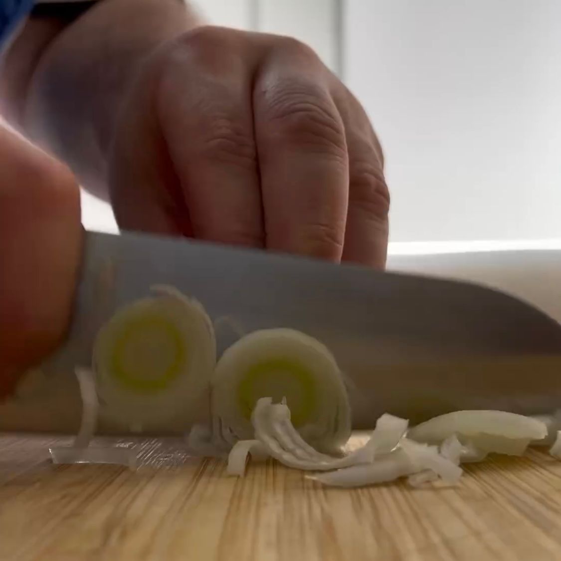 Una persona sta tagliando le cipolle su un tagliere di legno