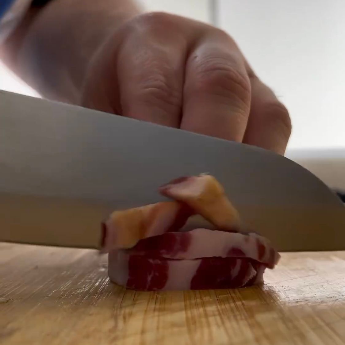 Una persona sta tagliando la pancetta su un tagliere