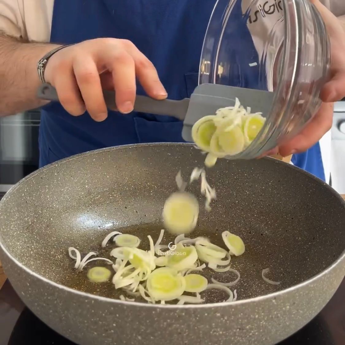 Una persona sta versando cipolle tritate in una padella