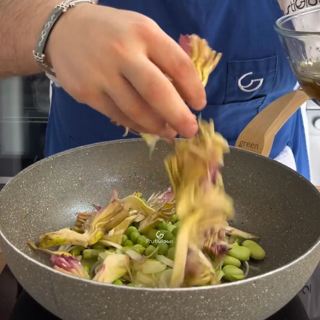 Una persona sta aggiungendo i carciofi in una padella