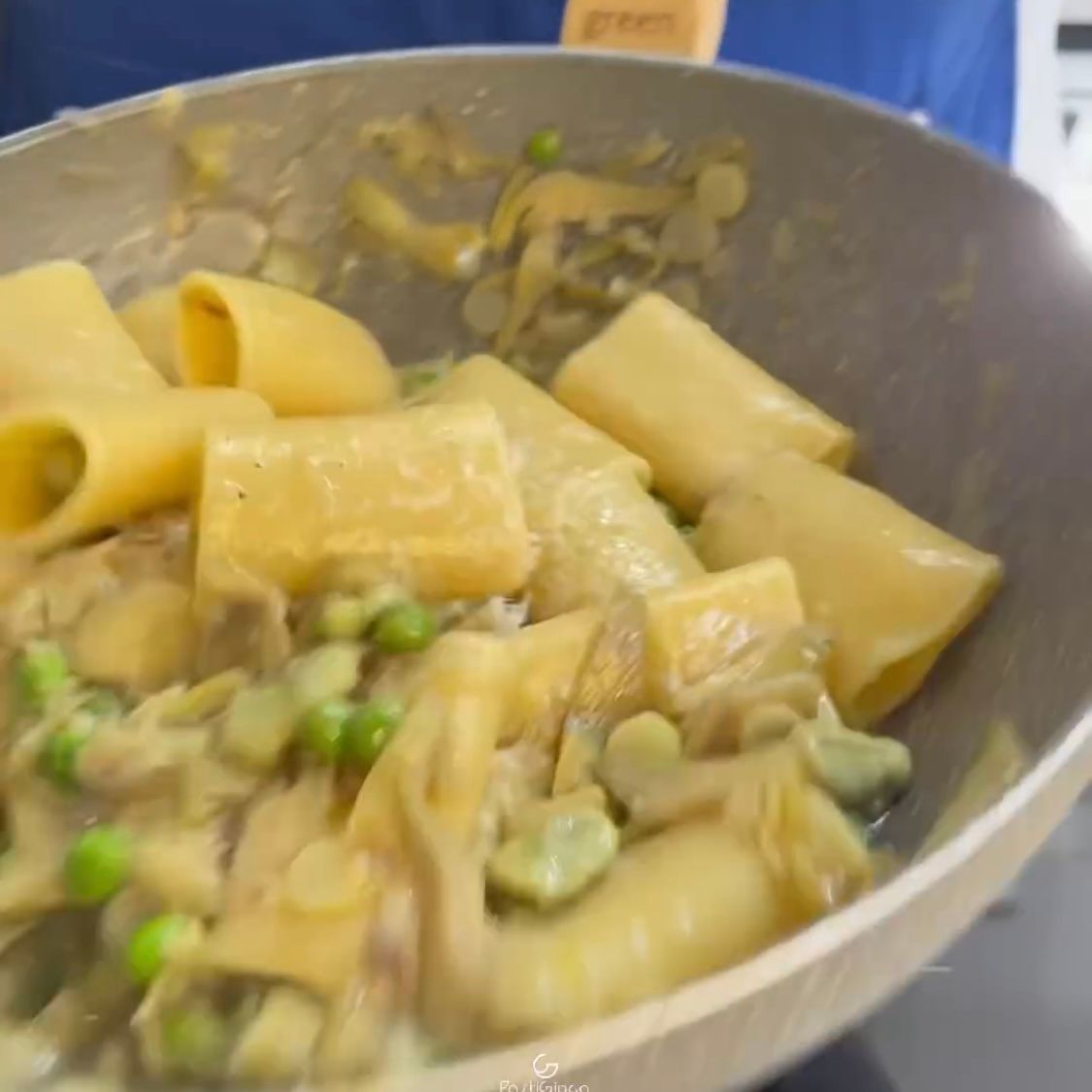 Una padella piena di pasta e piselli verdi