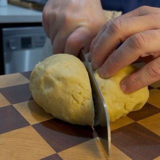 Una persona sta tagliando un pezzo di pasta su un tagliere