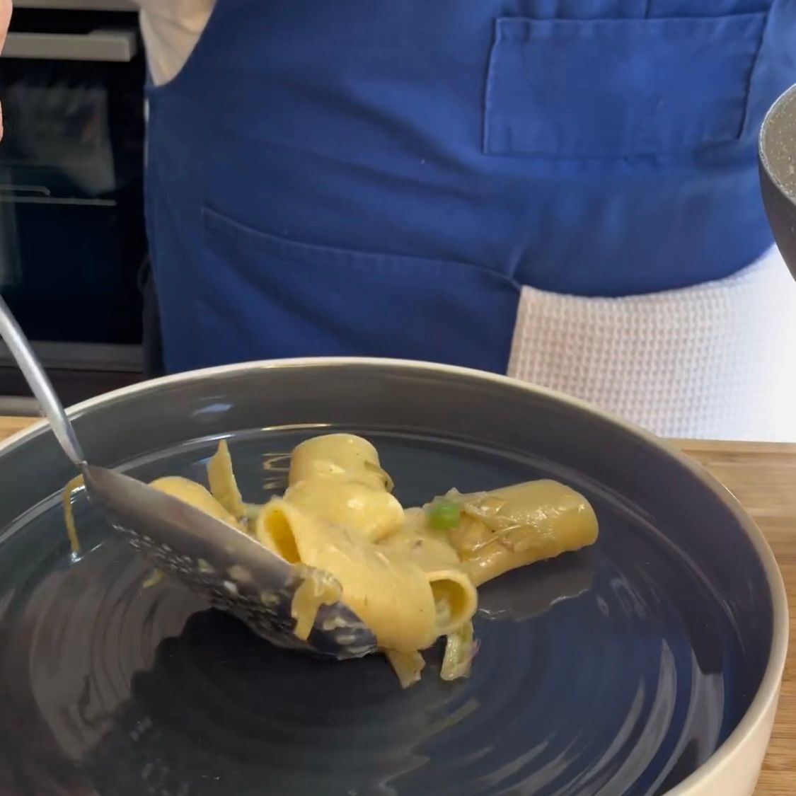 Una persona sta immergendo un cucchiaio in una ciotola di maccheroni al formaggio