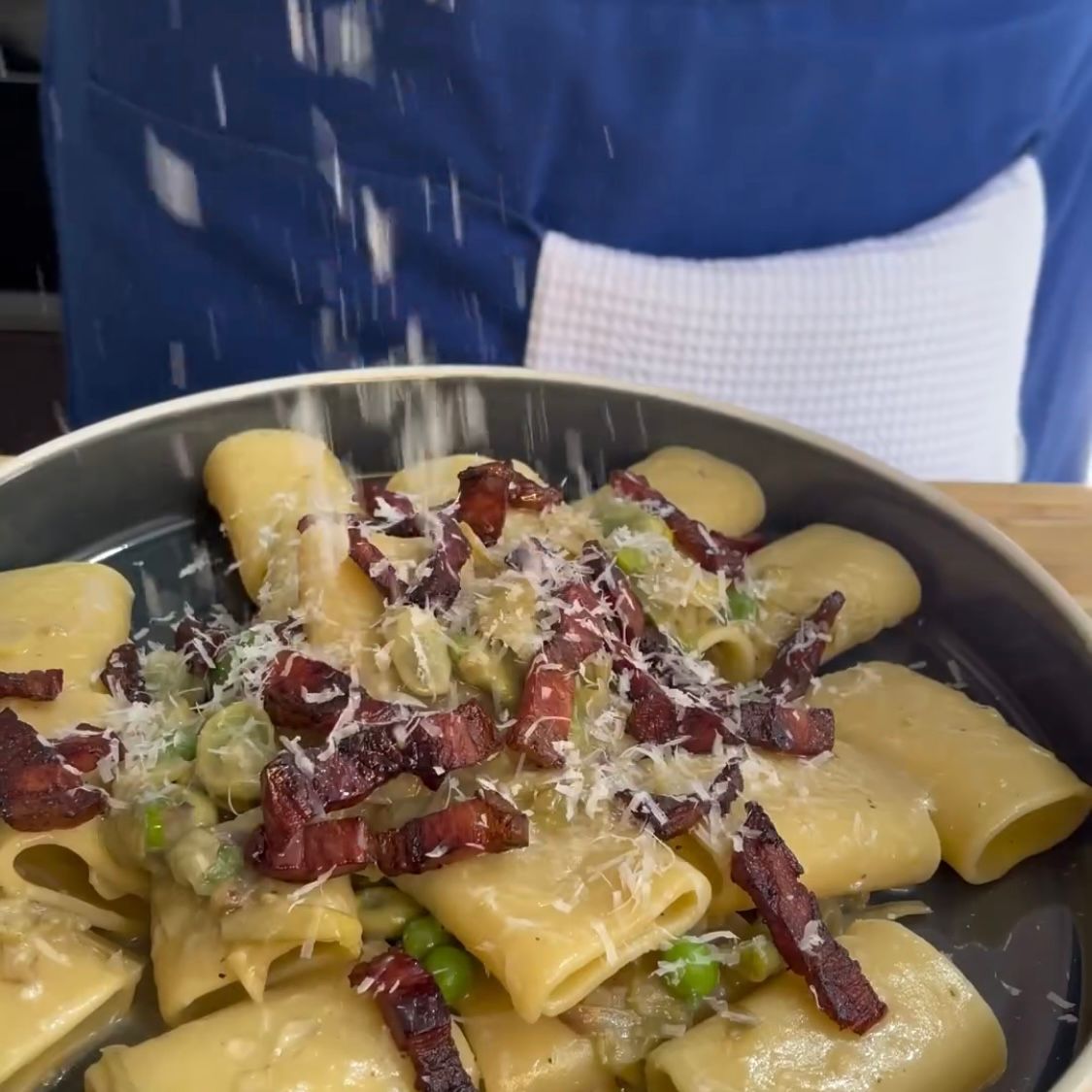 Una persona sta cospargendo il formaggio su un piatto di pasta