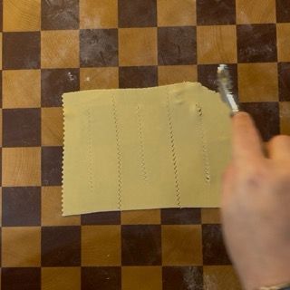 Una persona sta tagliando un pezzo di pasta su una tavola a scacchi