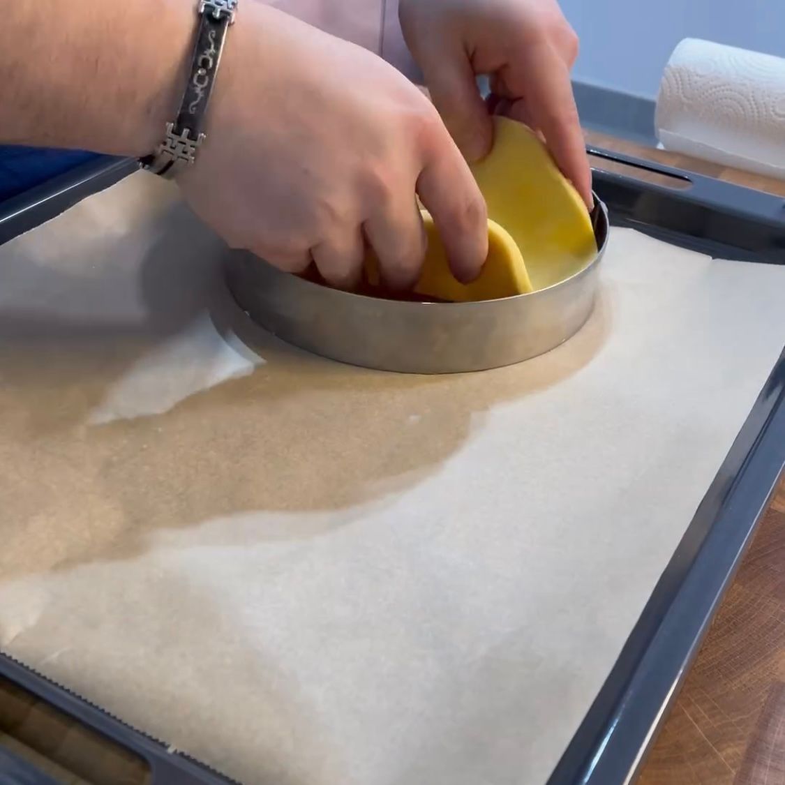 Una persona con un braccialetto al polso tiene in mano un oggetto giallo in un anello di metallo