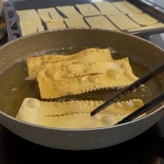 Una padella piena di cibo fritto e pinze